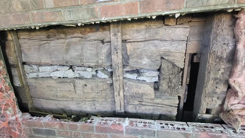 A stretch of hand hewn log wall with the chinking gone from between the courses.