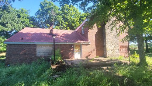 The house from the yard, the original log structure at one end and the later addition behind it.